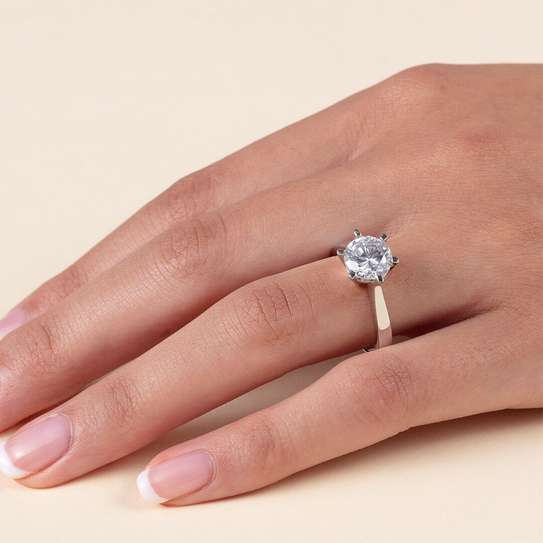 En gullring med stor diamant Et nærbilde av en godt vedlikehold kvinnehånd med diamantring. Dette er en gullring med seks klør som holder en stor diamant på plass.