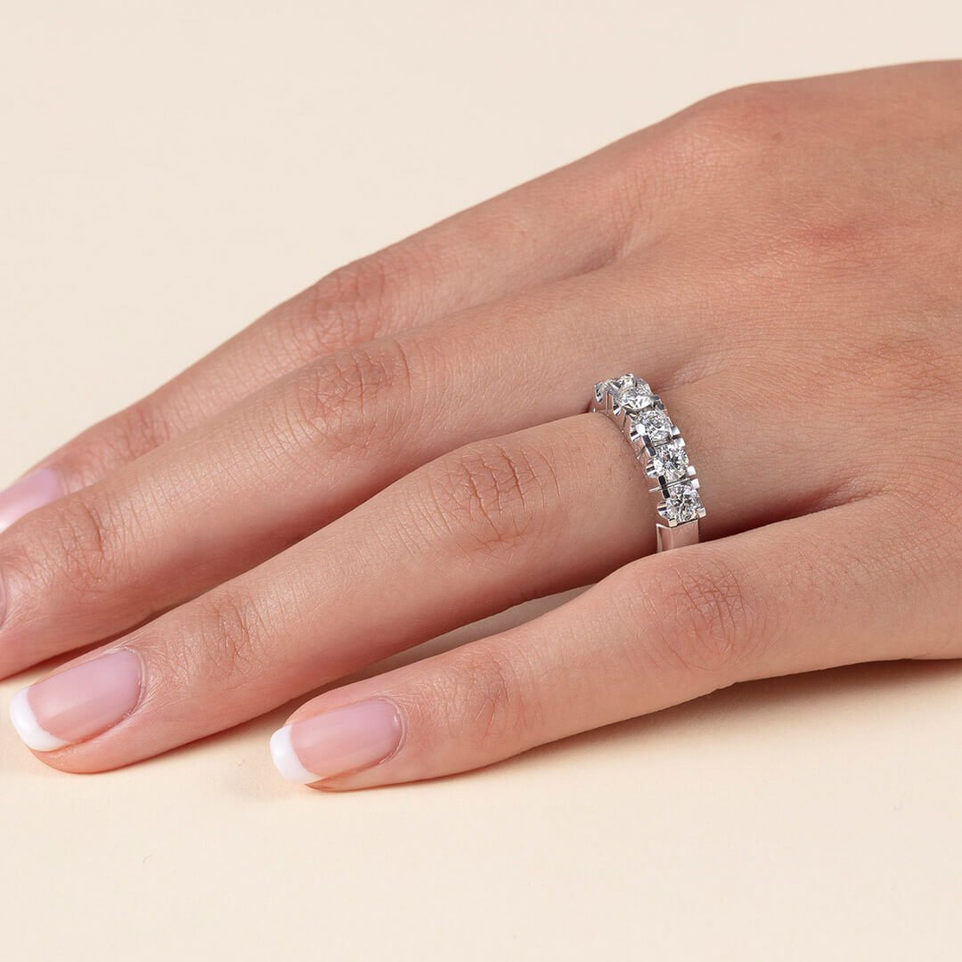 Et nærbilde av en godt vedlikehold kvinnehånd med diamantring. Dette er en ring med fire større diamanter dantert utover ringen.