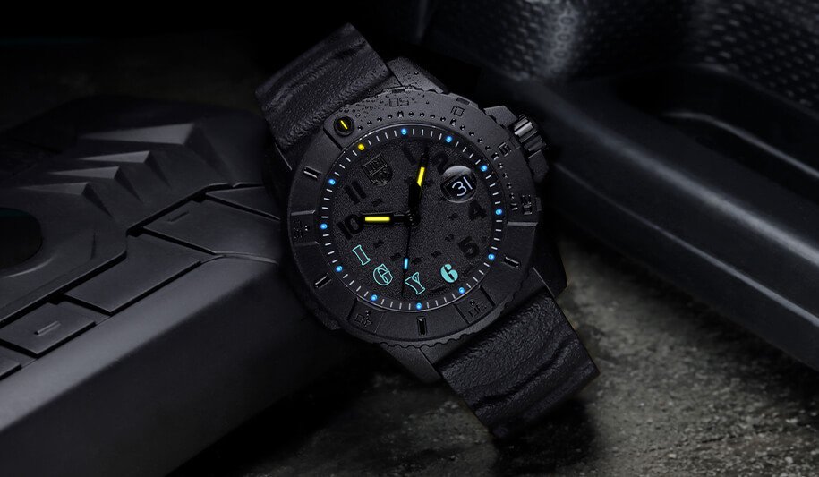 En sort sportsklokke fra Luminox med opplyste tall og IGY6 i lyseblått, som ligger sammen med svart plast, teppe og svart skinn.