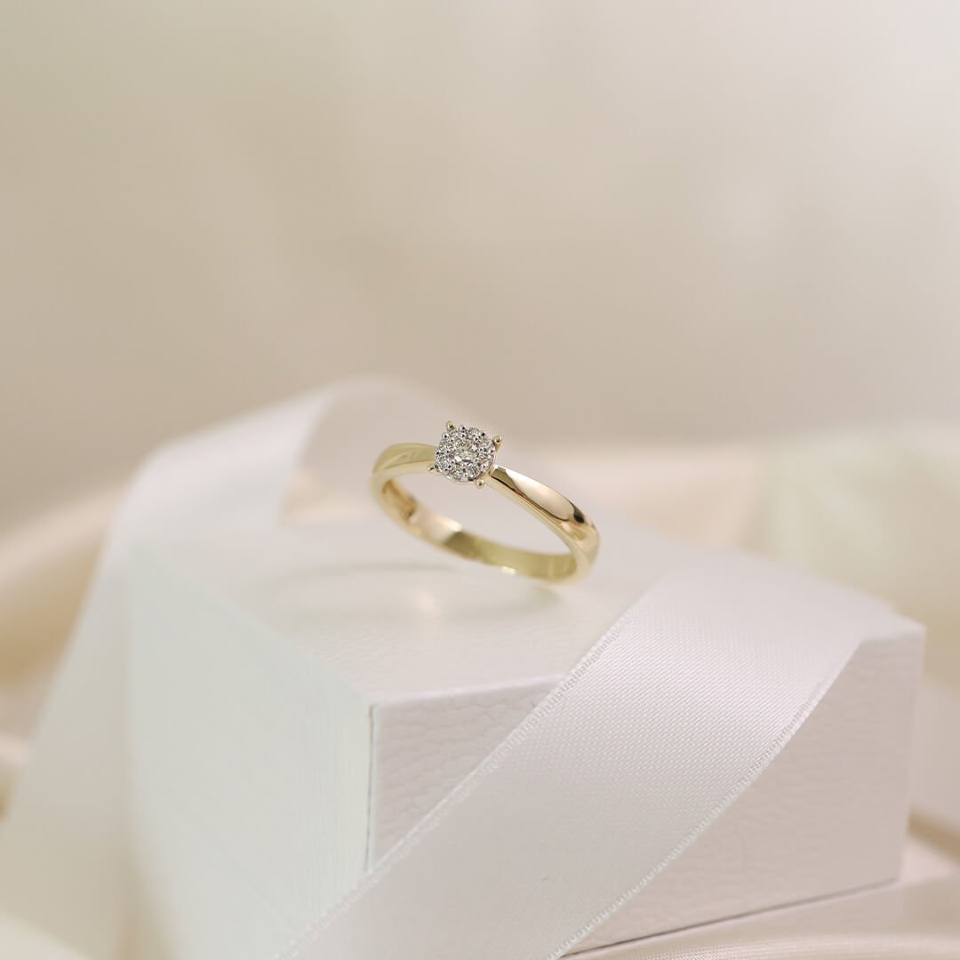 Ringer- tips til inspirasjon Gullring med diamant står på en hvit gaveeske med satengbånd i lys og myk bakgrunn.