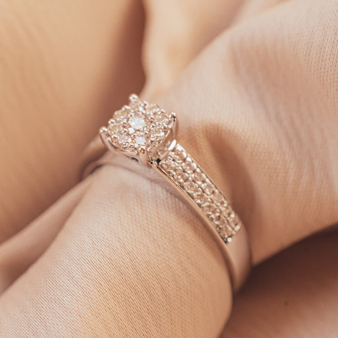 Diamantring En diamantring utstilt med en beige, skrukkete duk. Diamantringen har flere små stener i midten og halveis opp selve ringen.