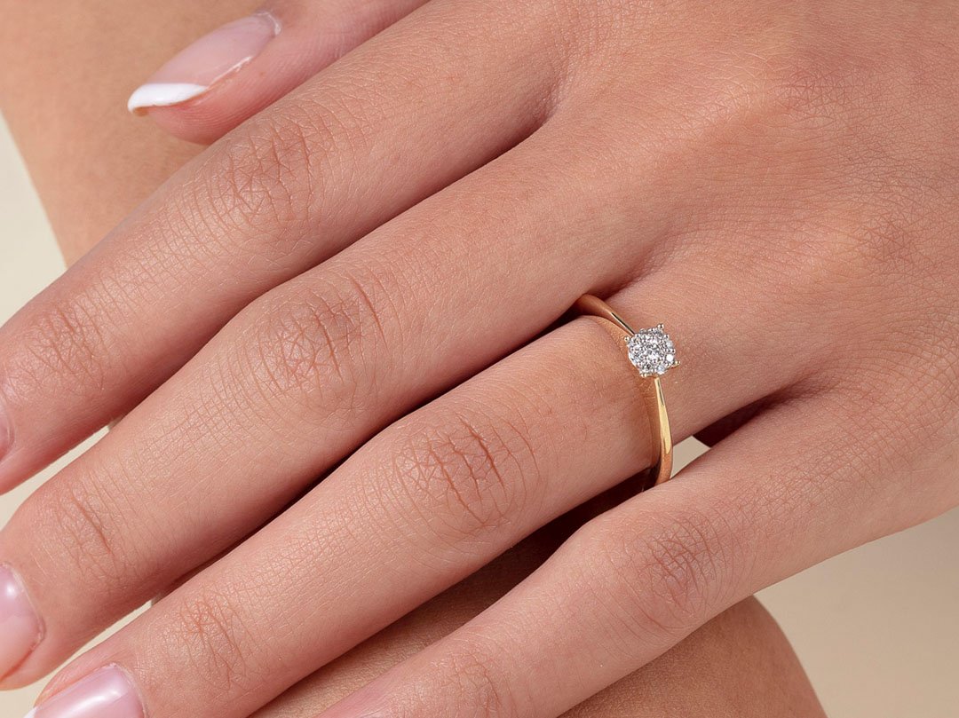 Kjøp til forlovelsesring fra Bjørklund En hånd med en vakker ring med en liten diamant, ligger over en arm som å kunne vise frem ringen bedre i bildet.